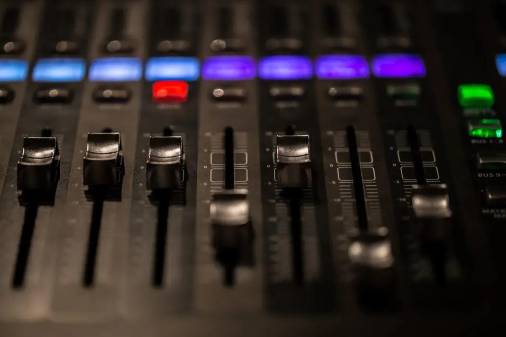 Close-up of an audio mixing console with illuminated buttons