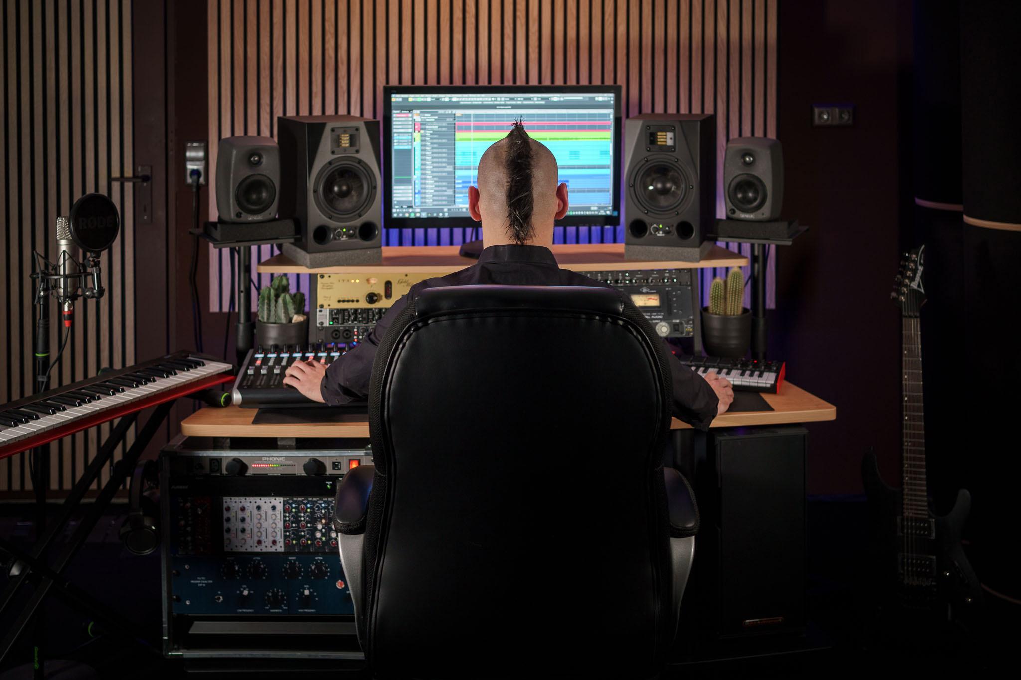 Person at a recording studio desk with monitors and musical equipment