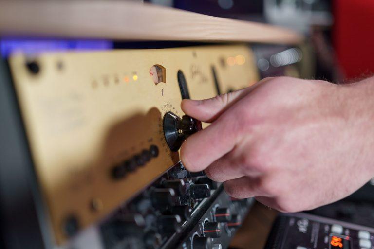 A hand adjusting a knob on a piece of audio equipment