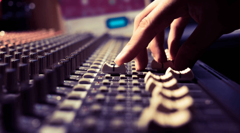 Person adjusting a slider on a large sound mixing console