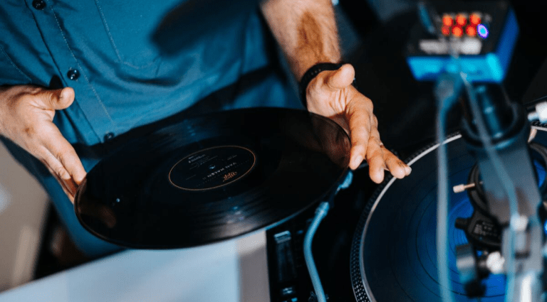 Person holding a vinyl record over a turntable